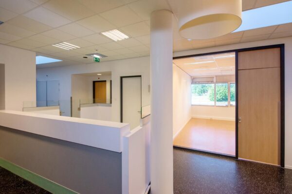 Modern interieur van het Harriet Freezerhof met een lichte gang en een open ruimte met grote ramen.